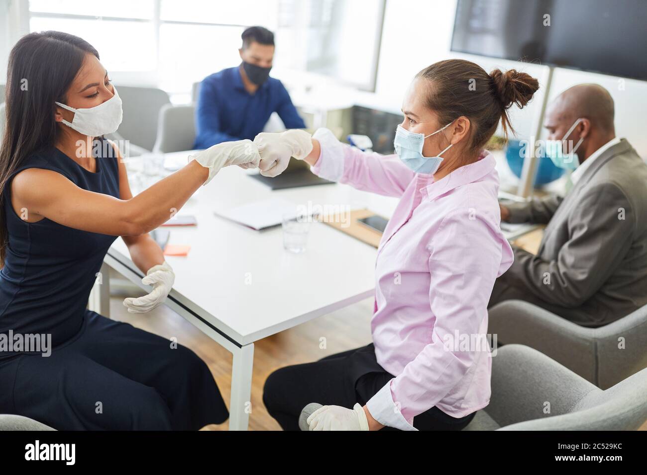 Two business women greet each other with a fist against the risk of infection with the corona virus Stock Photo