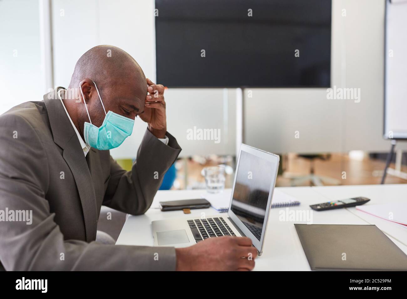 African business man wearing mask over Covid-19 on laptop computer is worried Stock Photo