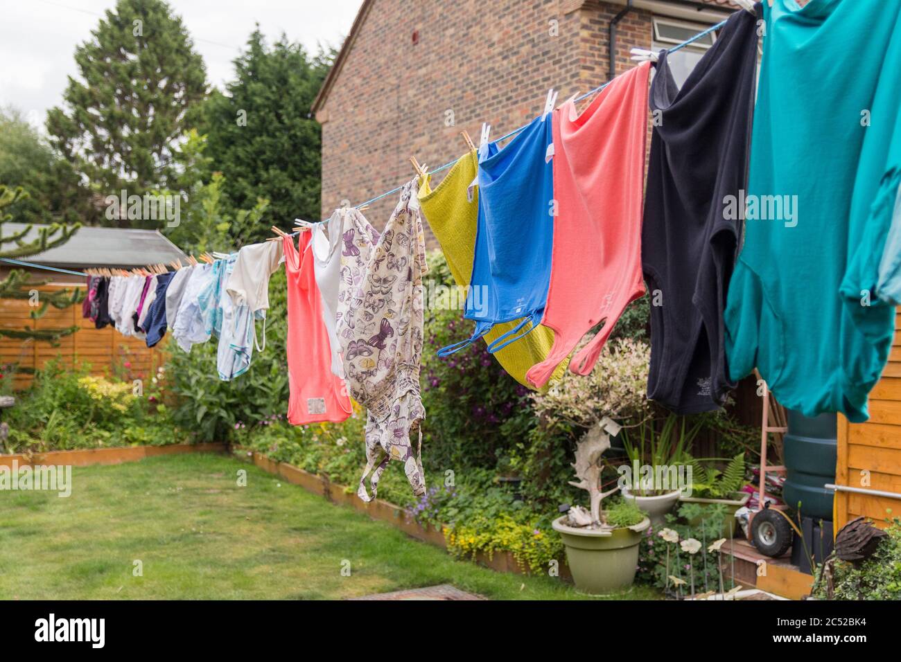 Washing hanging on long line drying in the gusty windy weather. Full length of my garden taken up with washing drying and blowing around end to end. Stock Photo