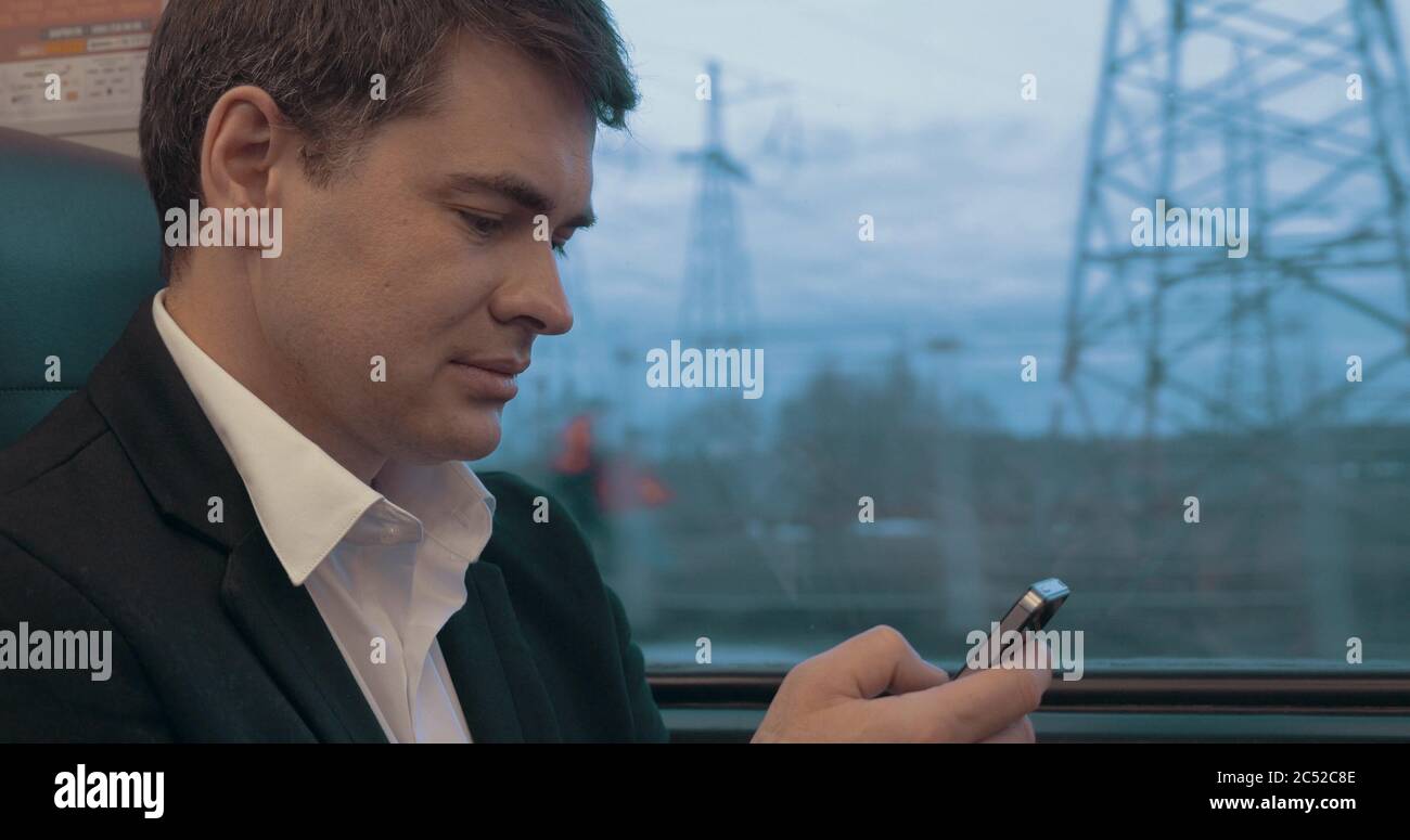 Businessman using smart phone during trip in train Stock Photo