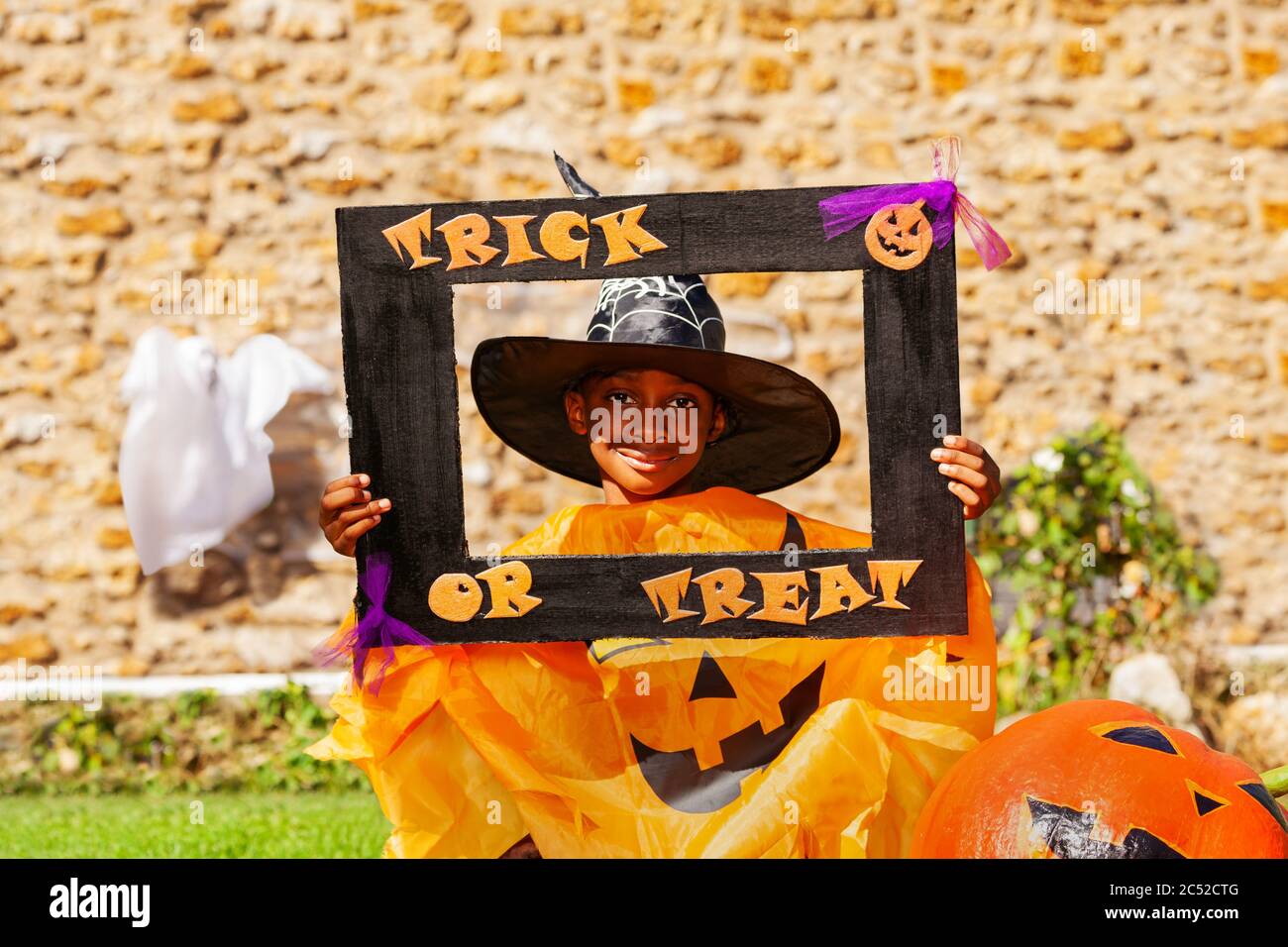 Halloween portrait of a black smiling handsome boy child in spooky costume with pumpkin hold trick or treat frame Stock Photo