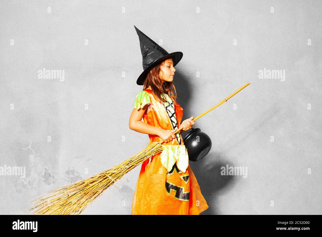 Portrait of a girl in Halloween costume stand with broom and bucket