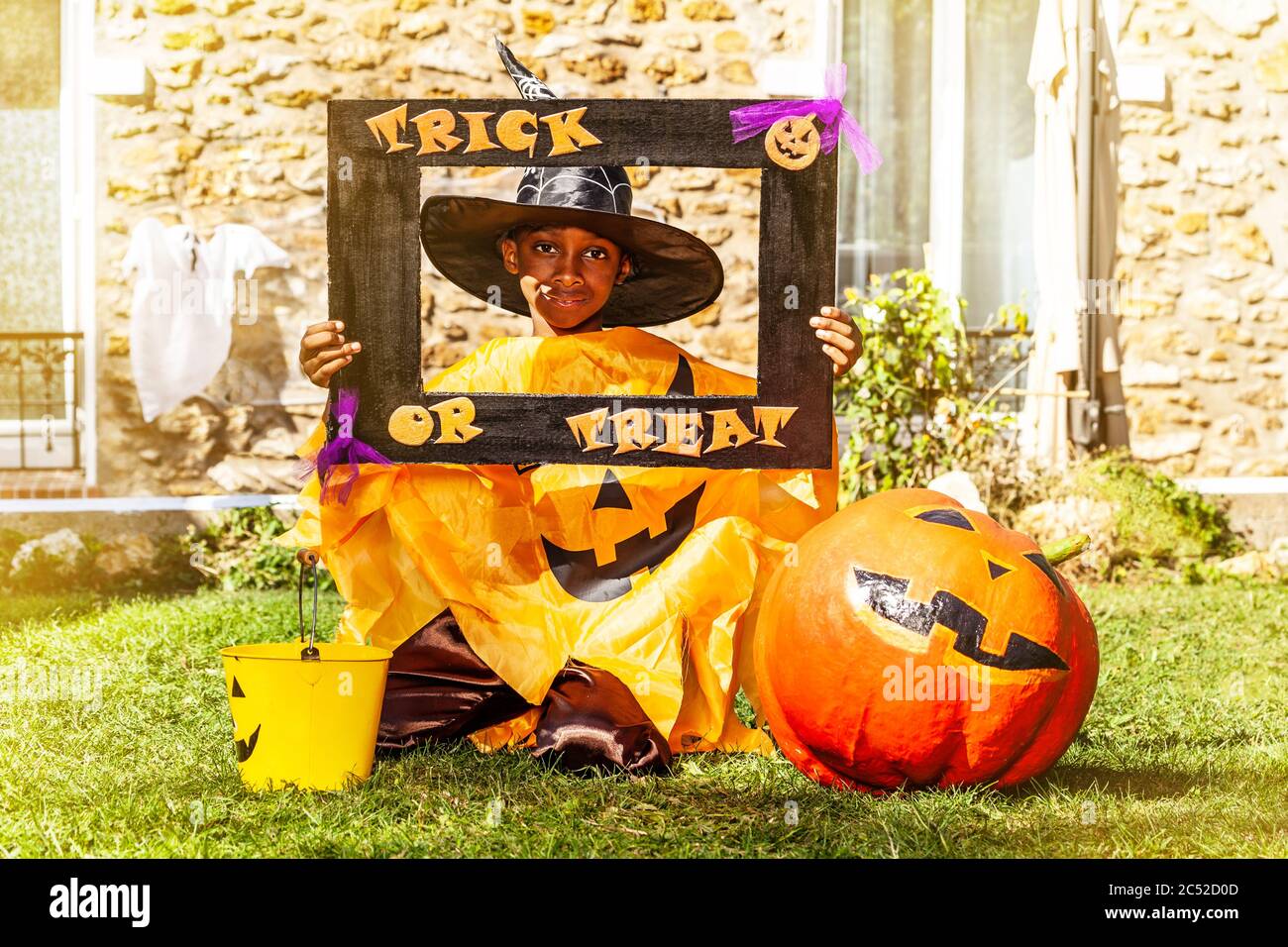 Halloween portrait of a black handsome boy in spooky costume with pumpkin hold trick or treat frame Stock Photo