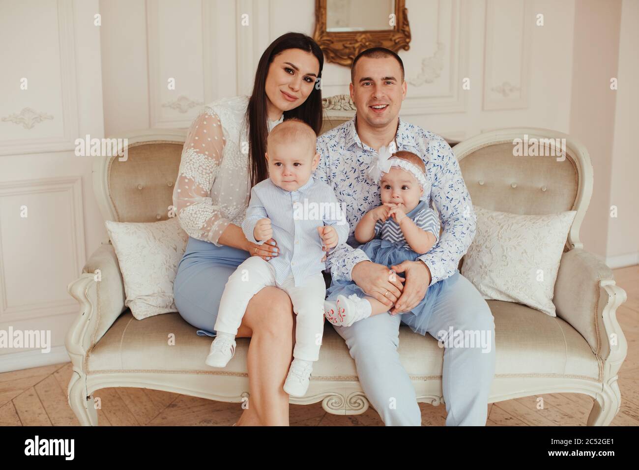 Portrait of a young couple sitting on a sofa with their  twins Stock Photo