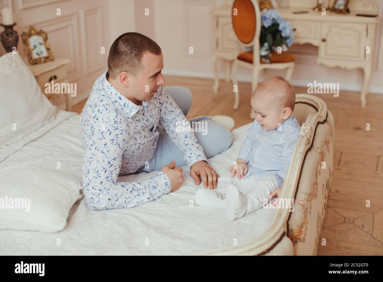 Father sitting on a bed with his baby son Stock Photo