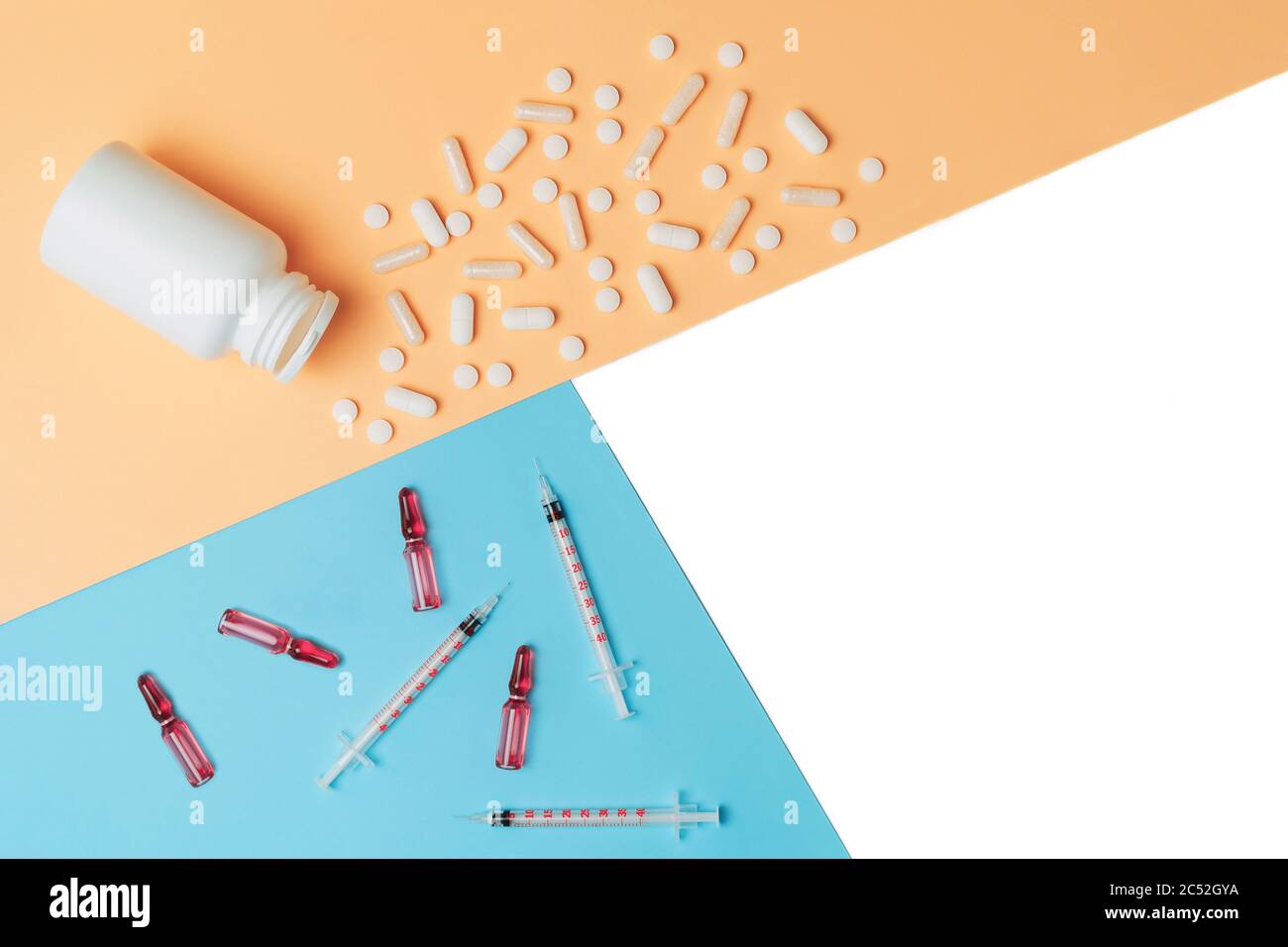 Mock-up bottle with spilled tablets and syringes with ampules on isolated white, orange and blue background. Cosmetology and medicine concept. Flat lay. Stock Photo