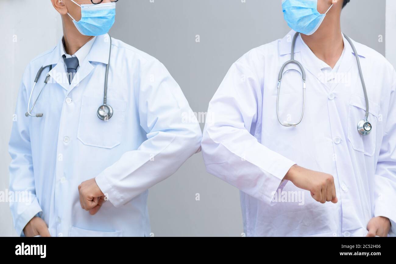 Two doctors bumping elbows instead of shaking hands Stock Photo