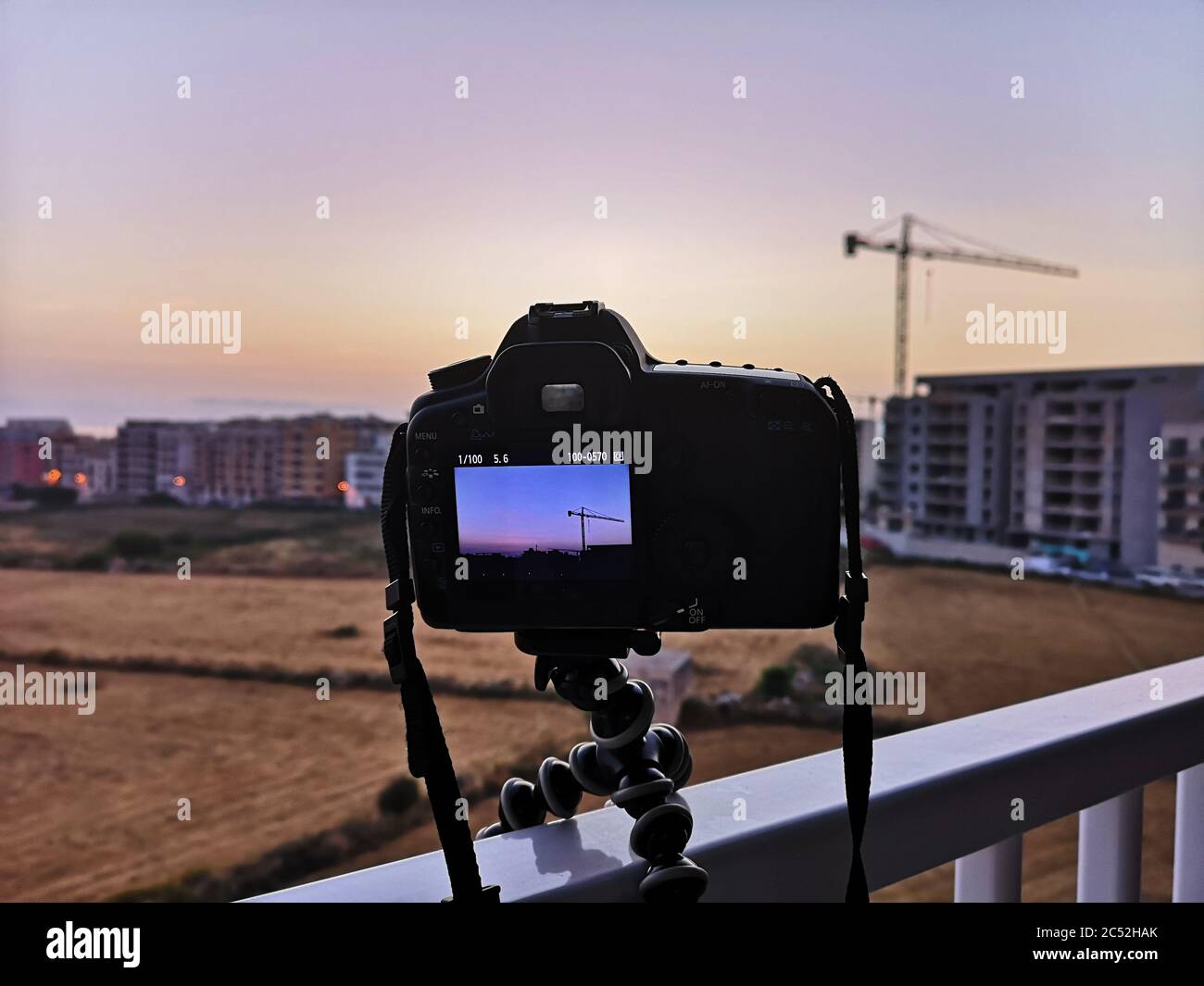 DSLR camera and tripod capturing city skyline at sunrise, Bugibba, Malta Stock Photo