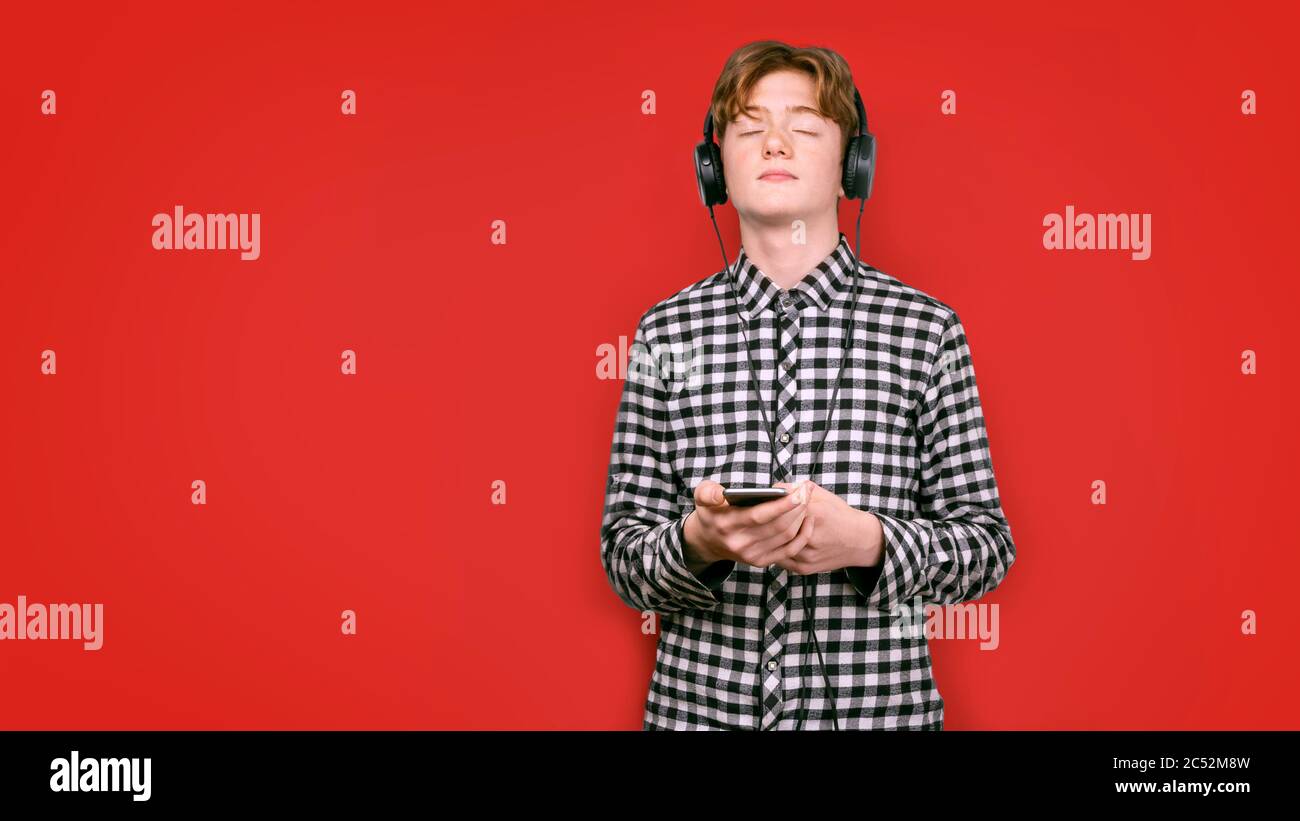 Teenager with red hair in a screeched shirt on a colored background. He ...