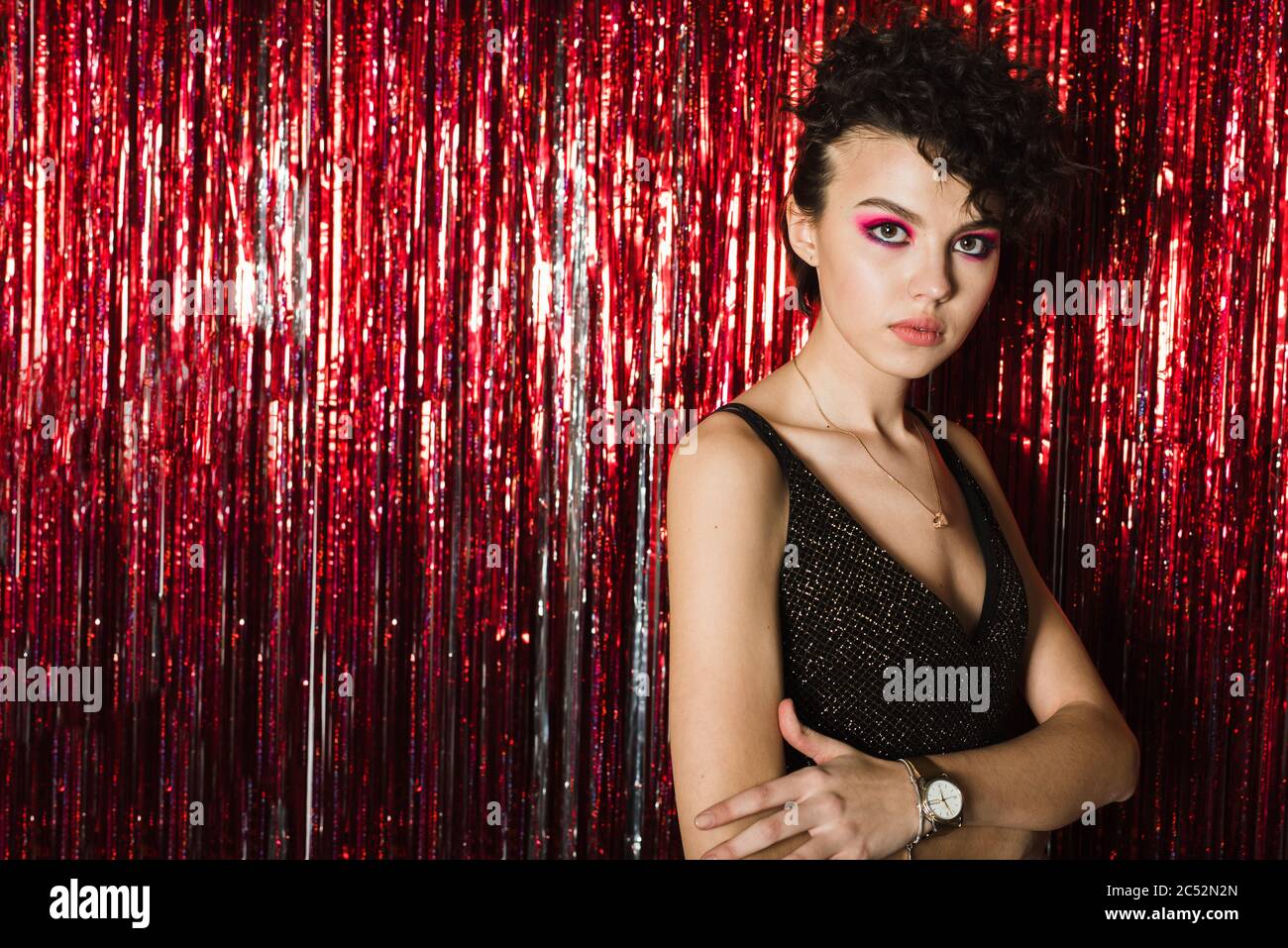 A teenager at a beautiful party on a background of red sequins in a flowing  shiny dress. Girl with a bright hairstyle and makeup Stock Photo - Alamy