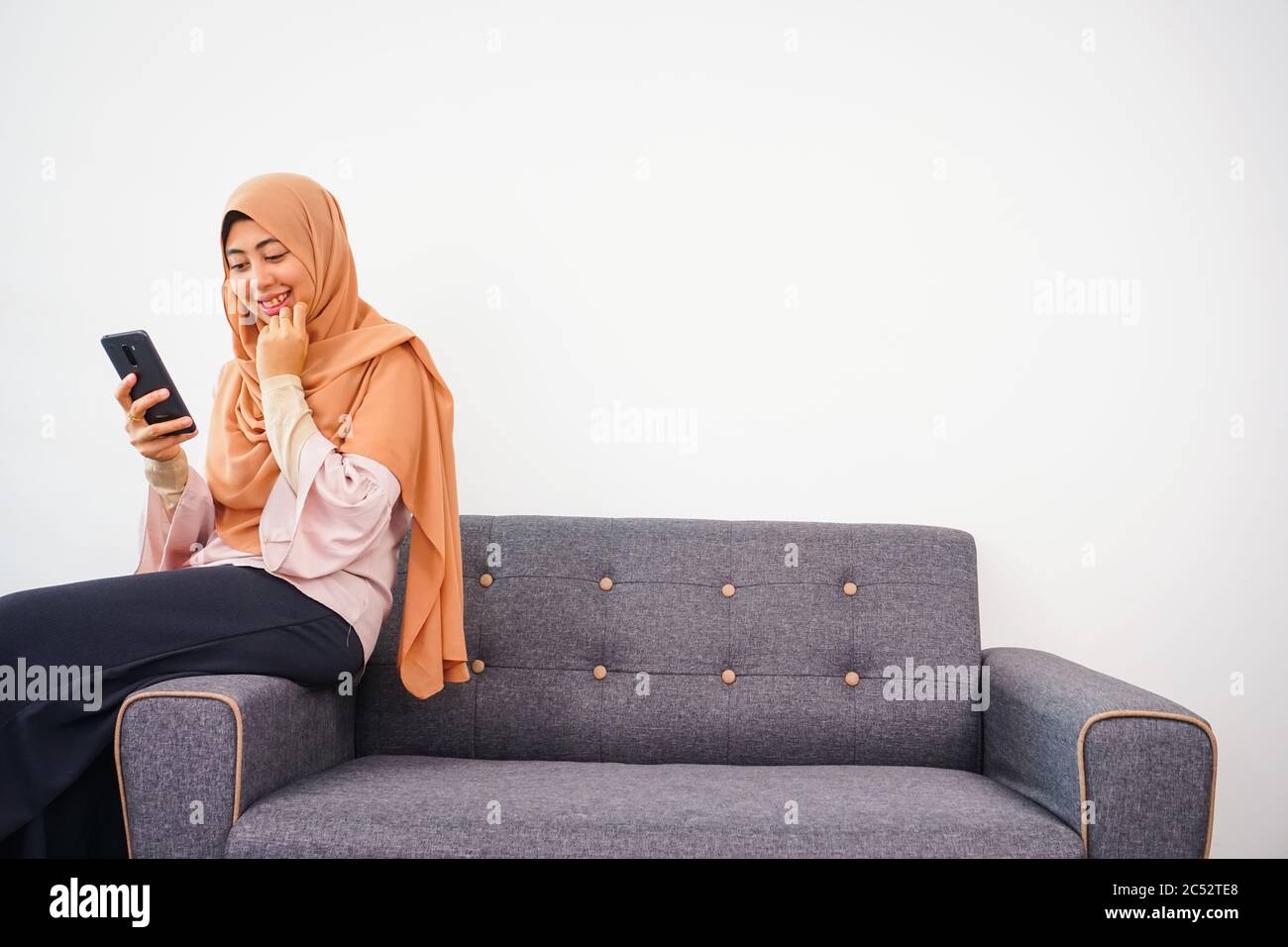 Happy young muslim woman sitting on sofa take self portrait with ...