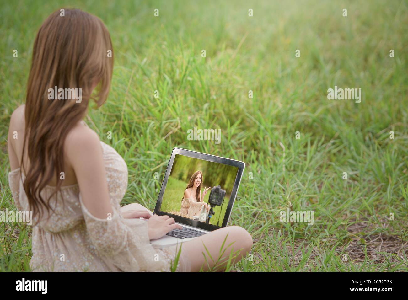 Woman sitting in a field reviewing vlogging filming, Thailand Stock Photo