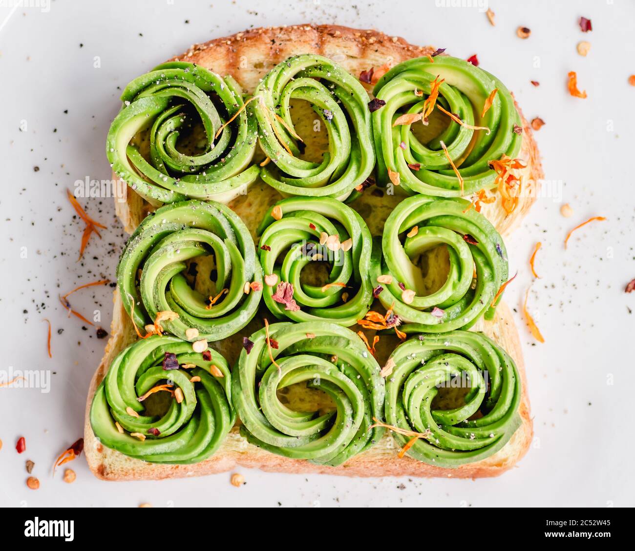 Toast with avocado roses, chilli flakes and edible flowers Stock Photo