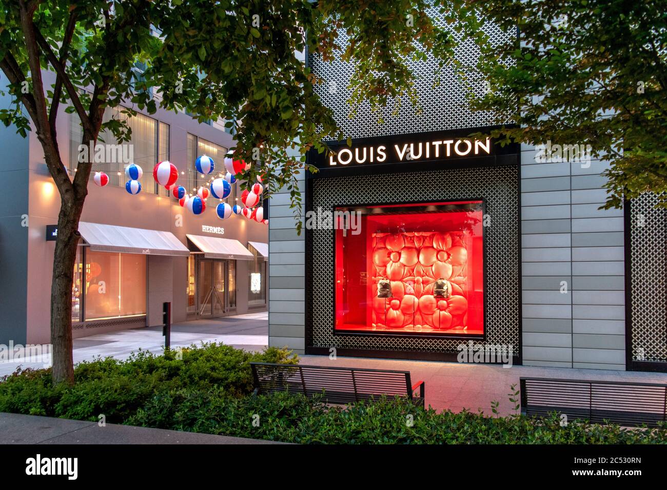 A red jeep parked in front of a louis vuitton store photo – Free