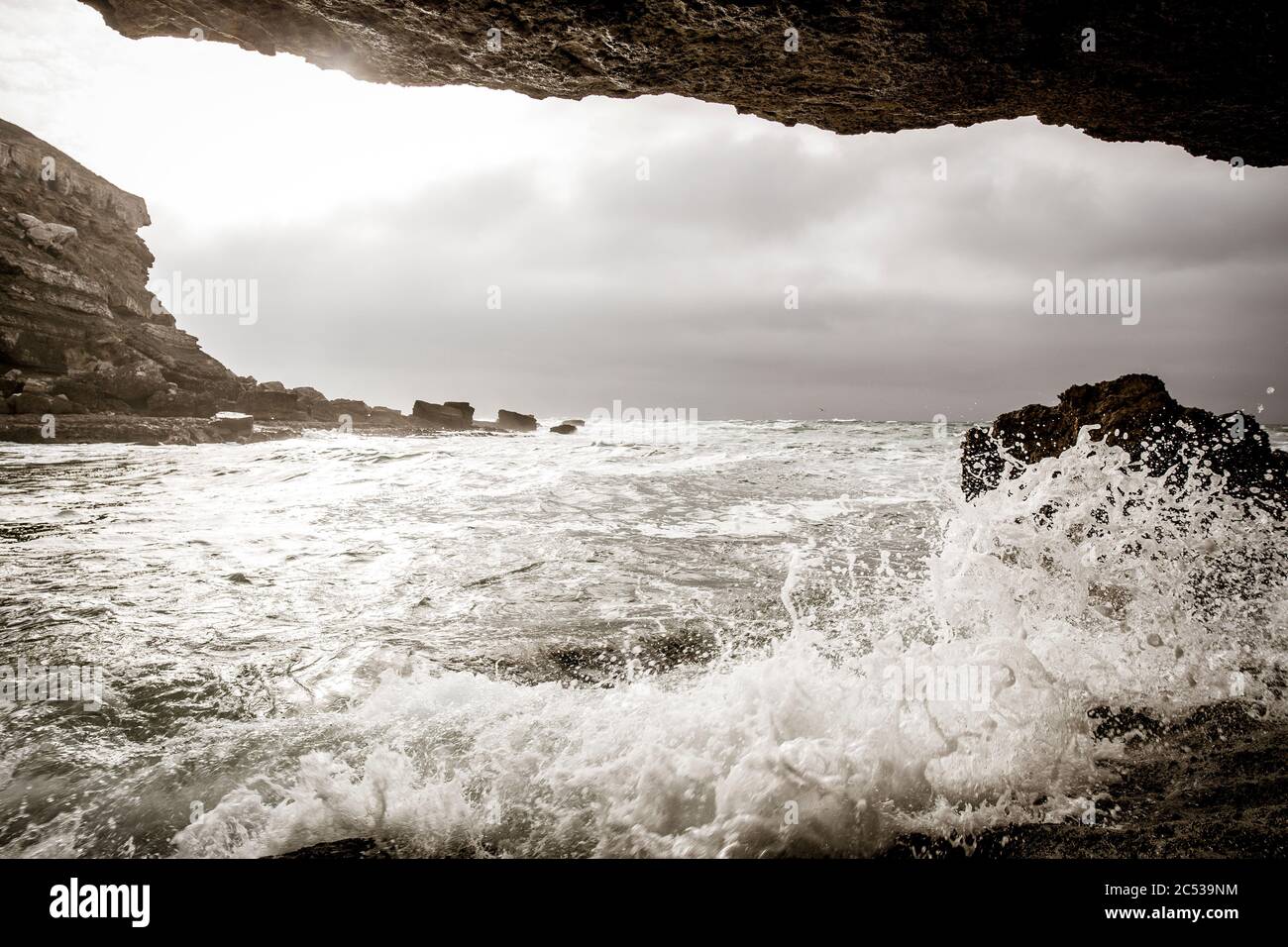 Waves break on rocks in a sea cave, Guincho, Portugal Stock Photo