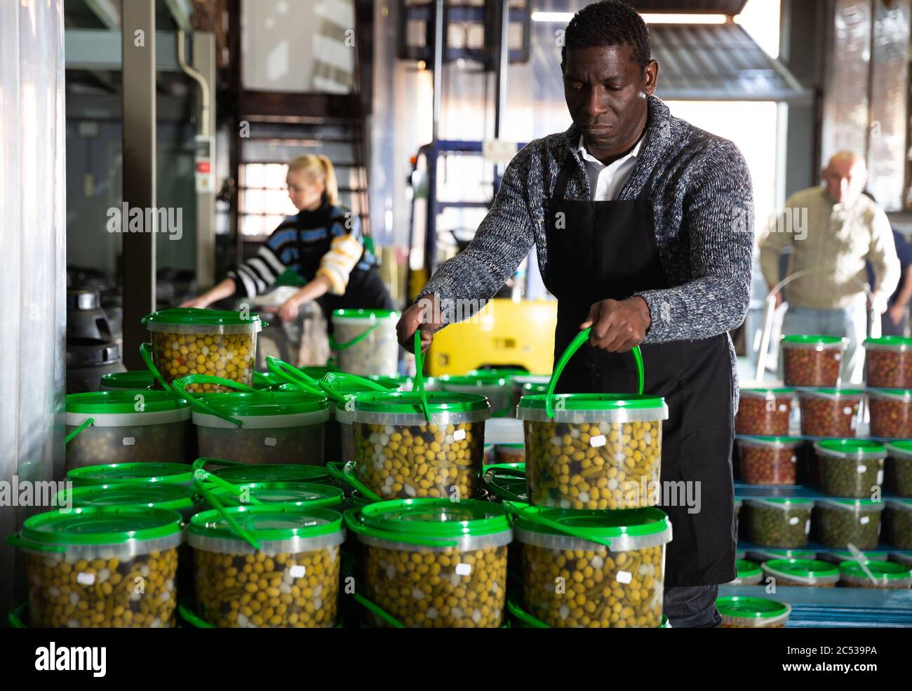 Workman carrying plastic containers with can olives Stock Photo Alamy