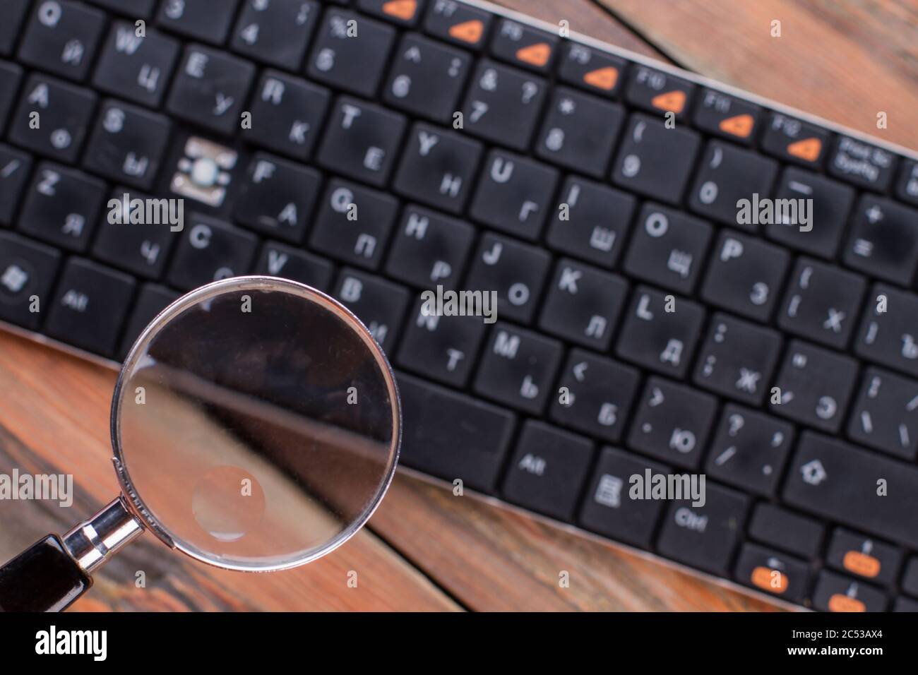 Magnifying glass over black keyboard Stock Photo Alamy