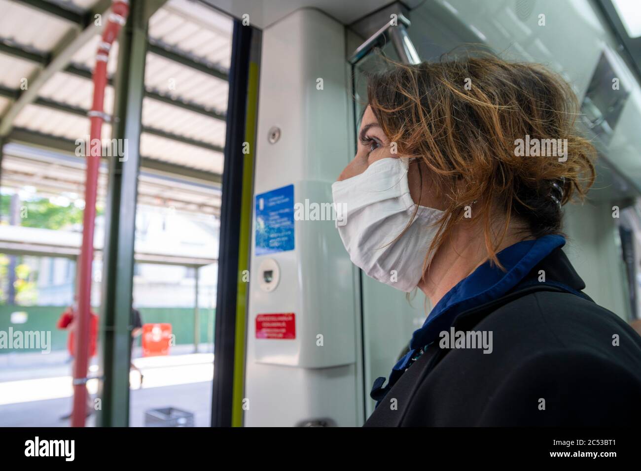 Woman passenger with protective face mask is waitng in a train station. Stock Photo