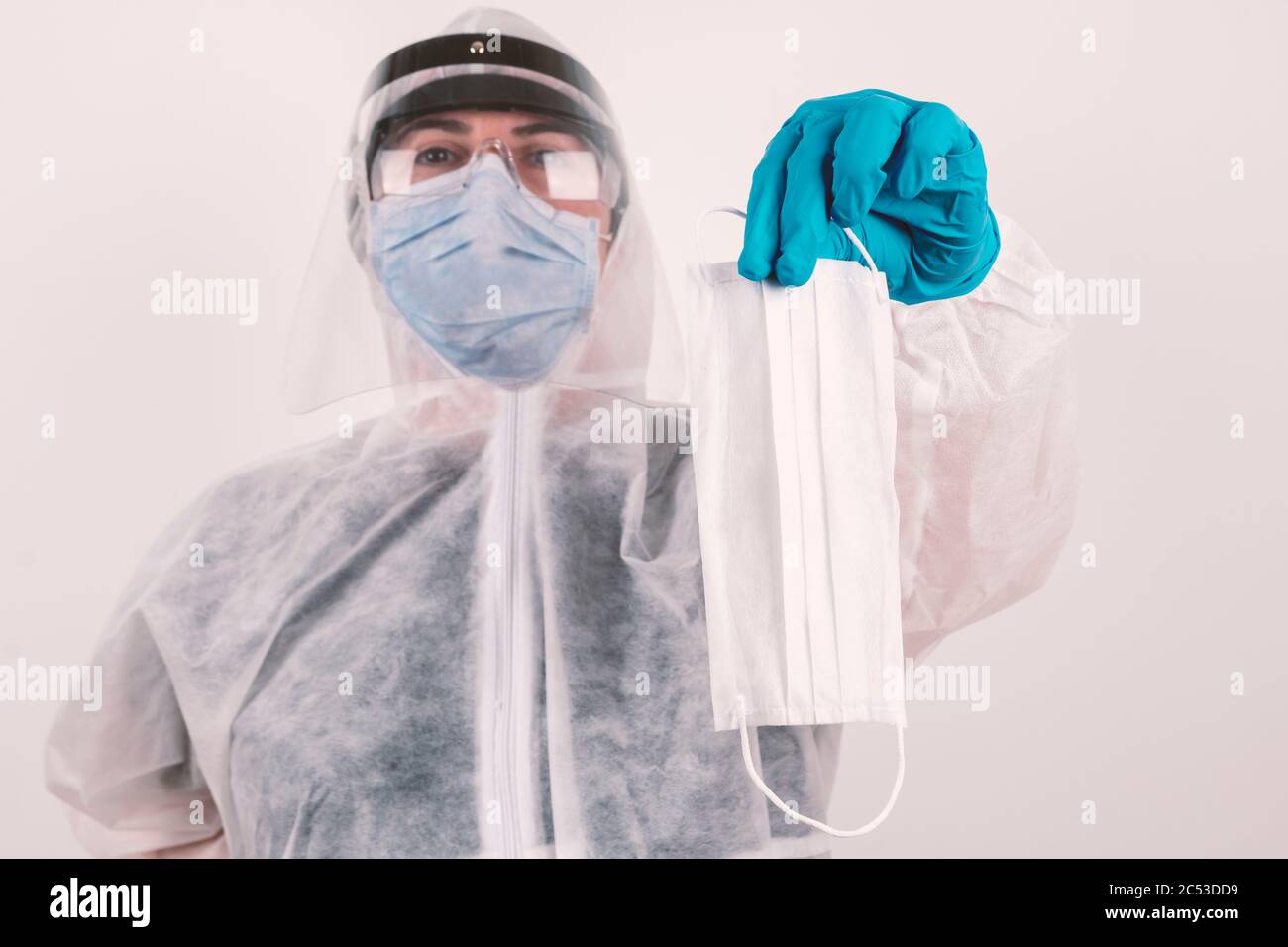 Laboratory scientist with blue mask, medical hygienic protection gloves and protective glasses holding and showing protective face mask. Stock Photo