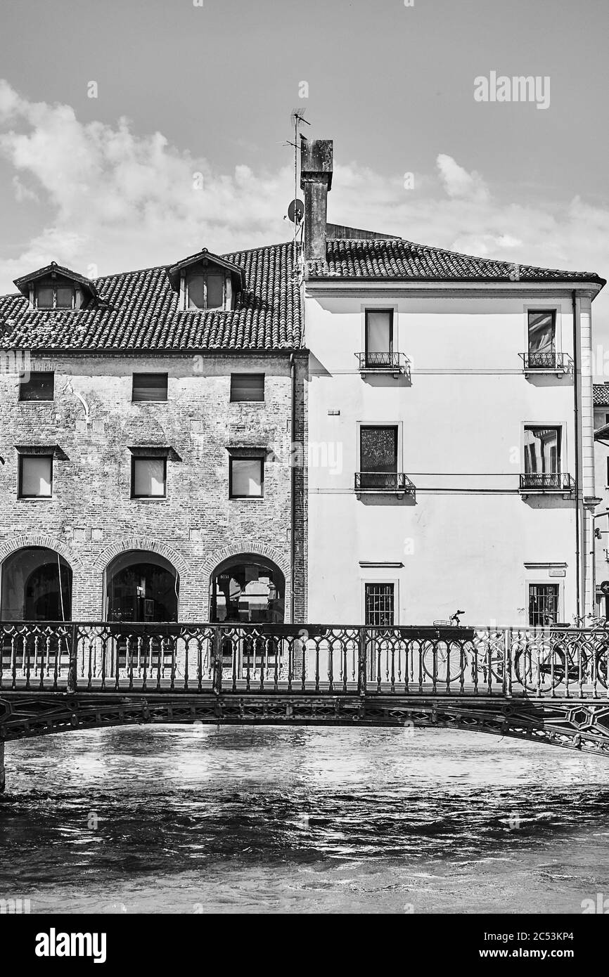 Old bridge and buildings by canal in Treviso town, Veneto, Italy. Black and white italian cityscape Stock Photo