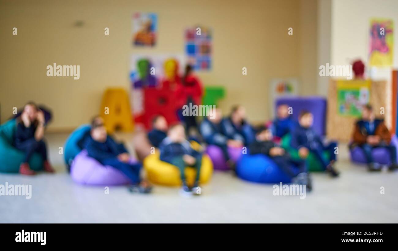 Children sits on multicolored bright chairs bags in the room for creative work, out of focus image Stock Photo