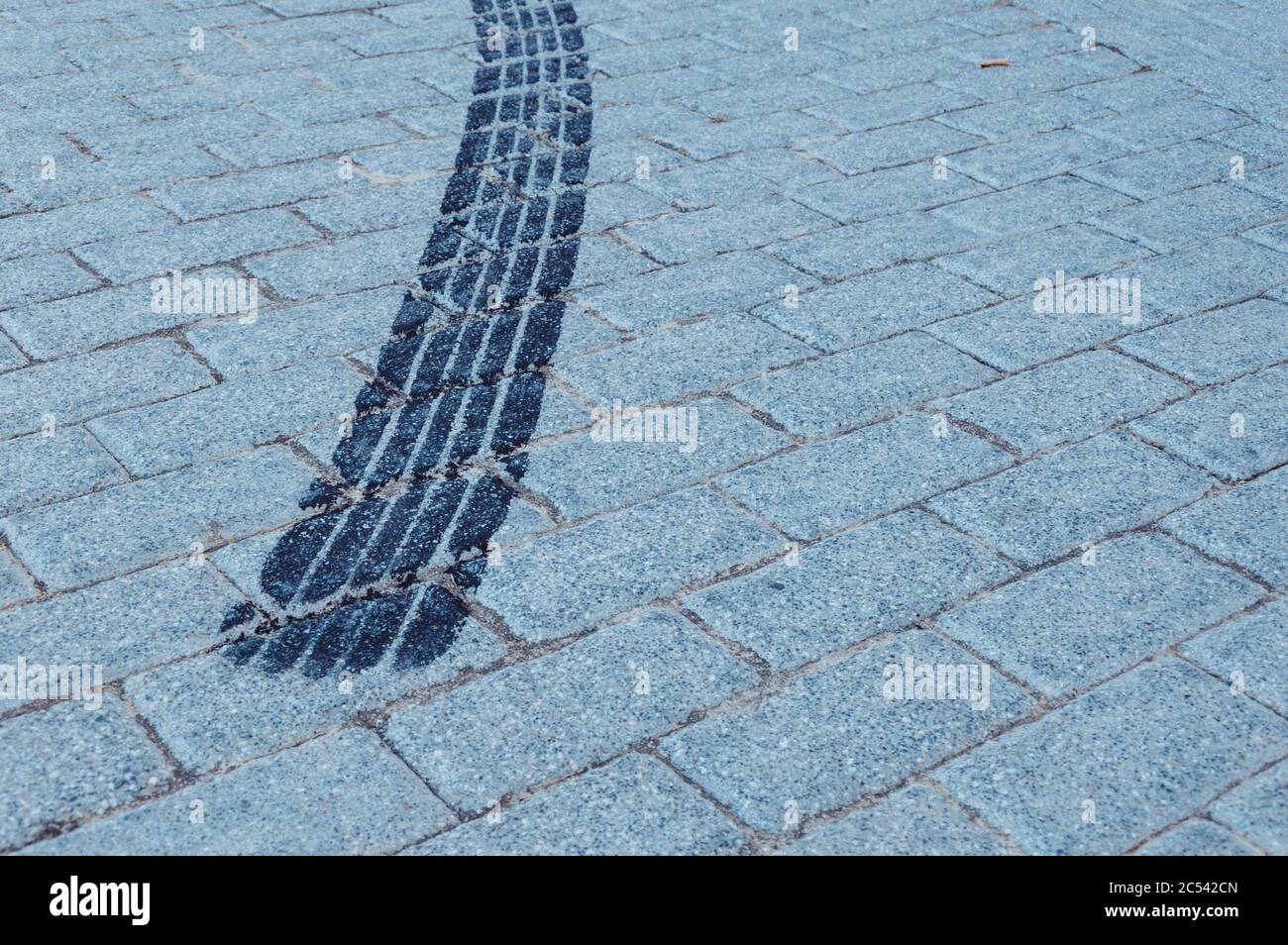 Black wheel trace on the cobblestone ground Stock Photo