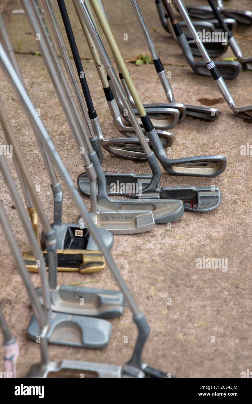 Golf clubs lined up against wall at putting green Stock Photo Alamy