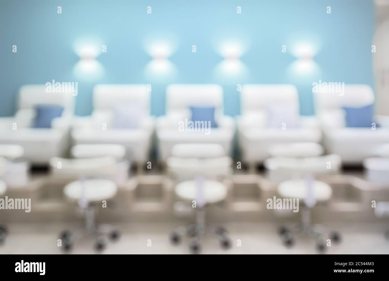 Nail salon interior as creative abstract blur background. Pedicure armchairs in a modern salon. Inside a beauty studio with white and blue design. Row Stock Photo