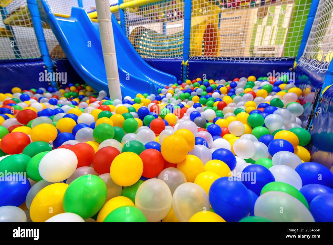 Kids playground indoor. Panoramic view inside the dry pool with colorful balls and slide. Nice plastic gym for activity in playroom. Closeup of colore Stock Photo