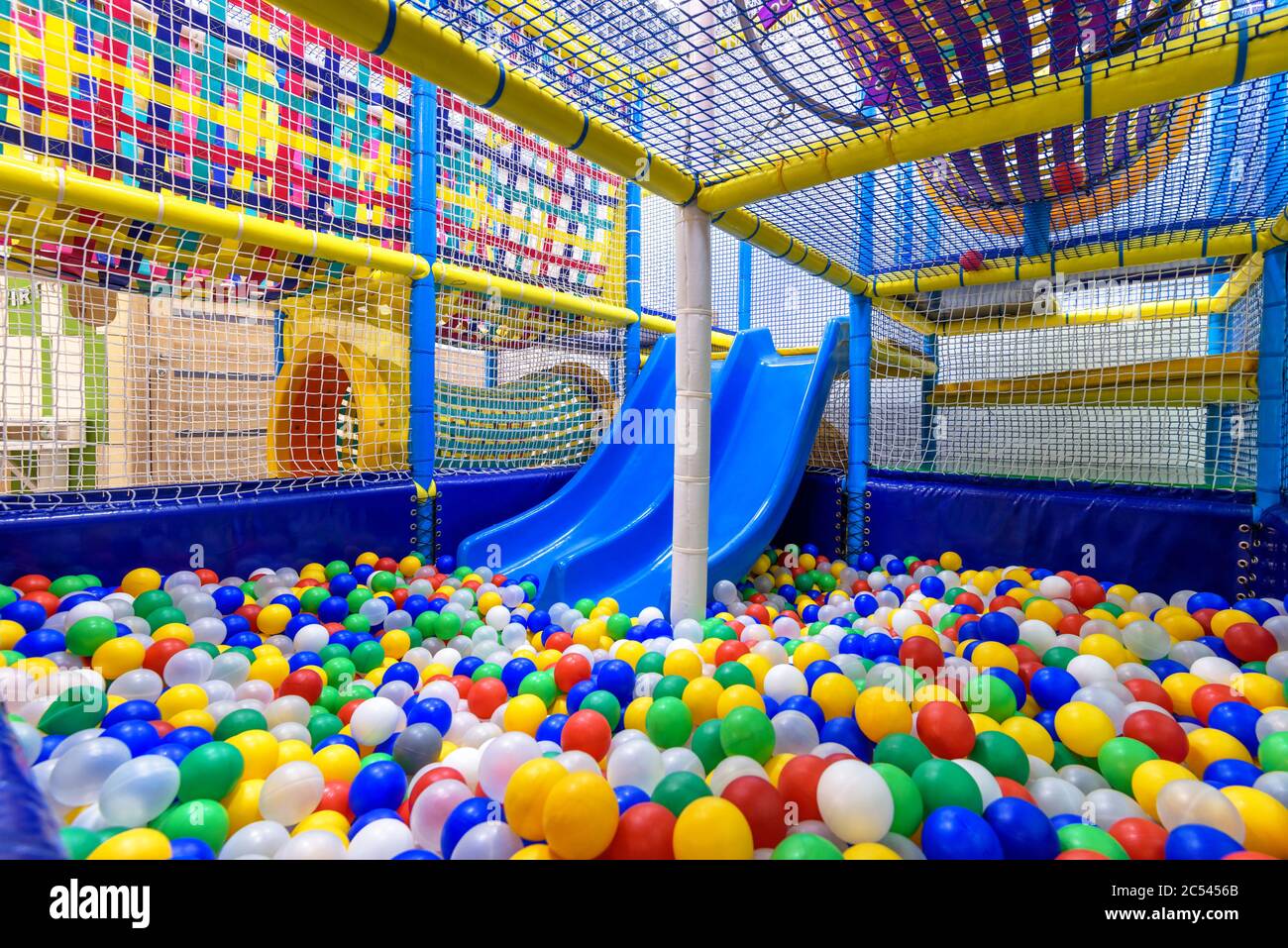 Kids playground indoor. Panoramic view inside the dry pool with colorful balls and slide. Nice plastic gym for activity in playroom. Children playgrou Stock Photo