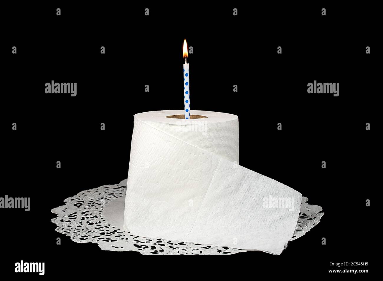 birthday candle in white toilet paper roll on lace paper doily isolated on black Stock Photo