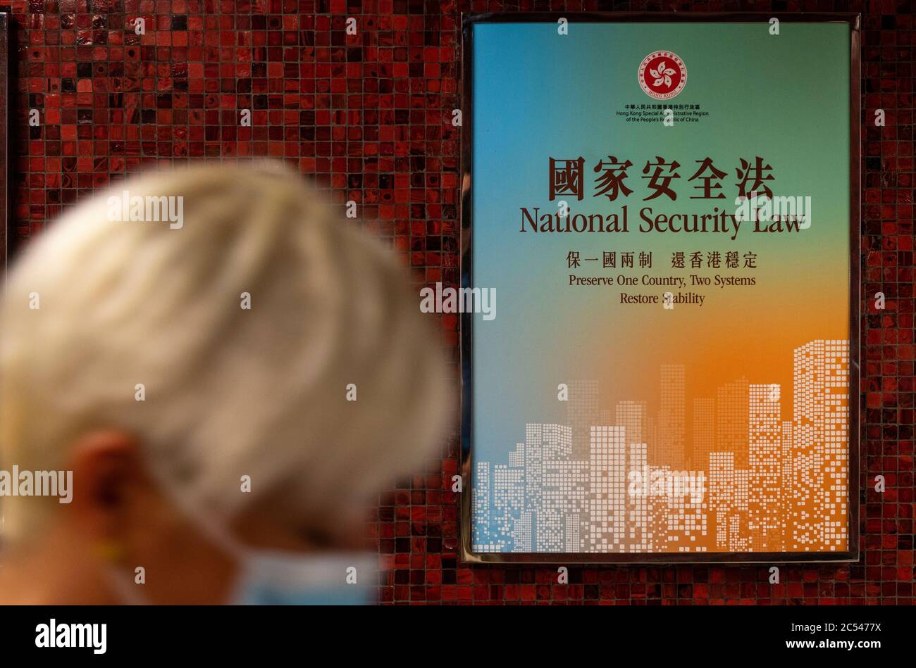 A commuter walks past a government-sponsored advertisement promoting the national security law passed in Hong Kong. Stock Photo