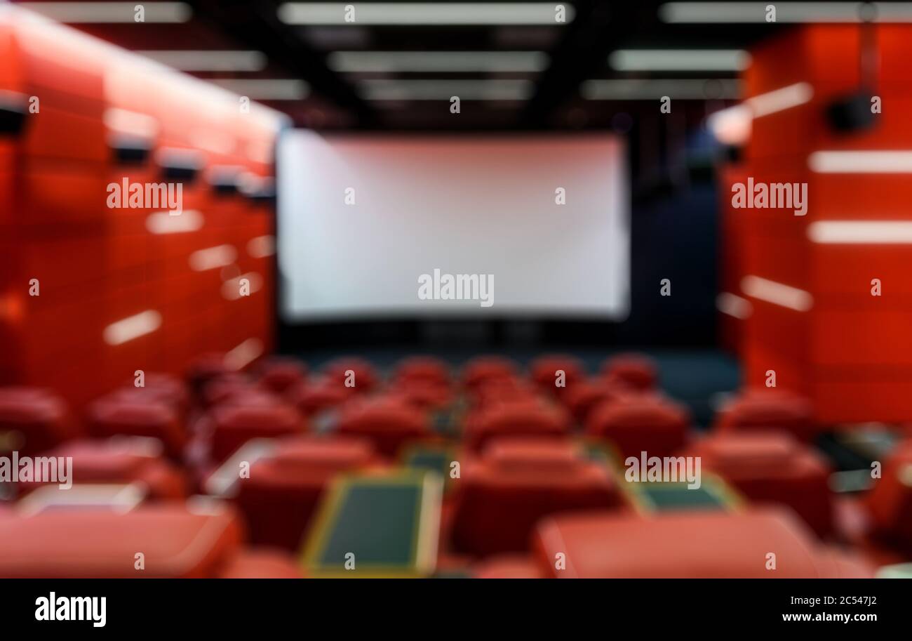 Panorama of an empty cinema hall as creative abstract blur background. Contemporary red cinema auditorium design with a screen. Modern movie theater i Stock Photo