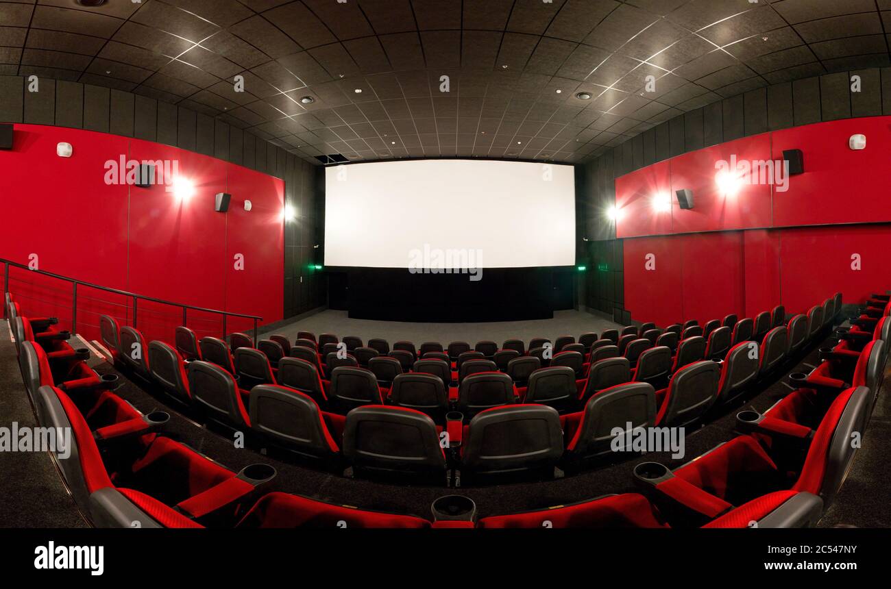 Moscow - Feb 9, 2012: Panoramic view of an empty cinema hall with a screen. Contemporary cinema auditorium design with red seats. Not full spherical p Stock Photo