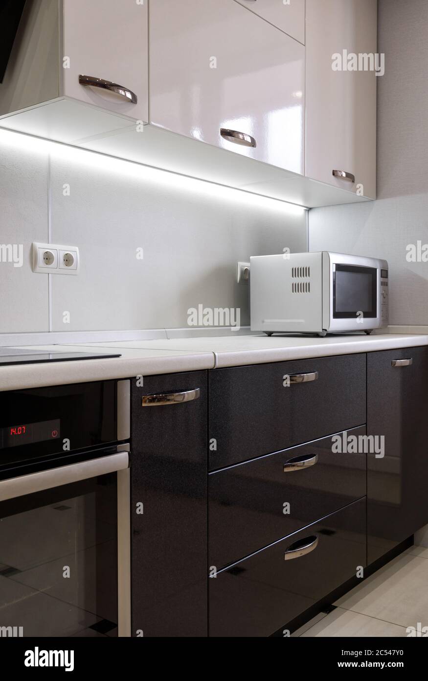 Interior of modern kitchen with microwave and oven. Interior of kitchen with bright and dark furniture. Stock Photo