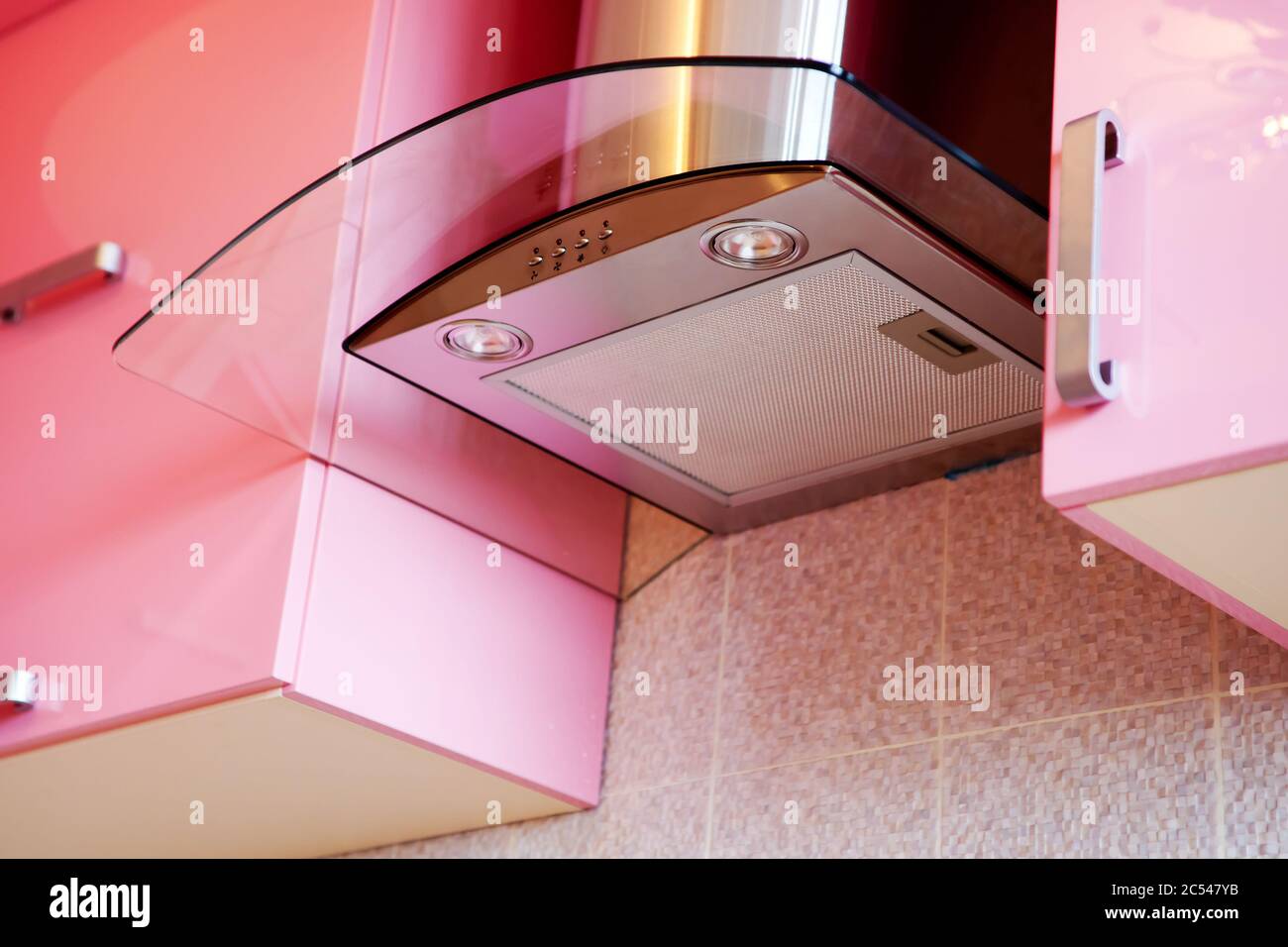 Metallic extractor hood in a pink kitchen. Detail of the modern kitchen interior. Cooker hood with contemporary design. Stock Photo