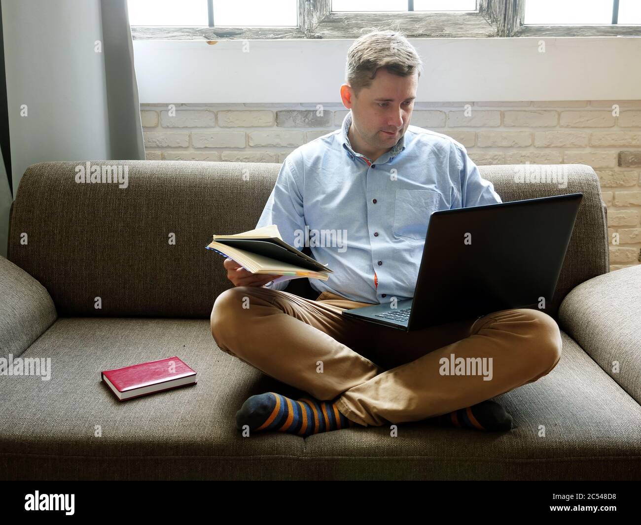 Distance education. A young guy on a sofa at home studying with a laptop. Stock Photo
