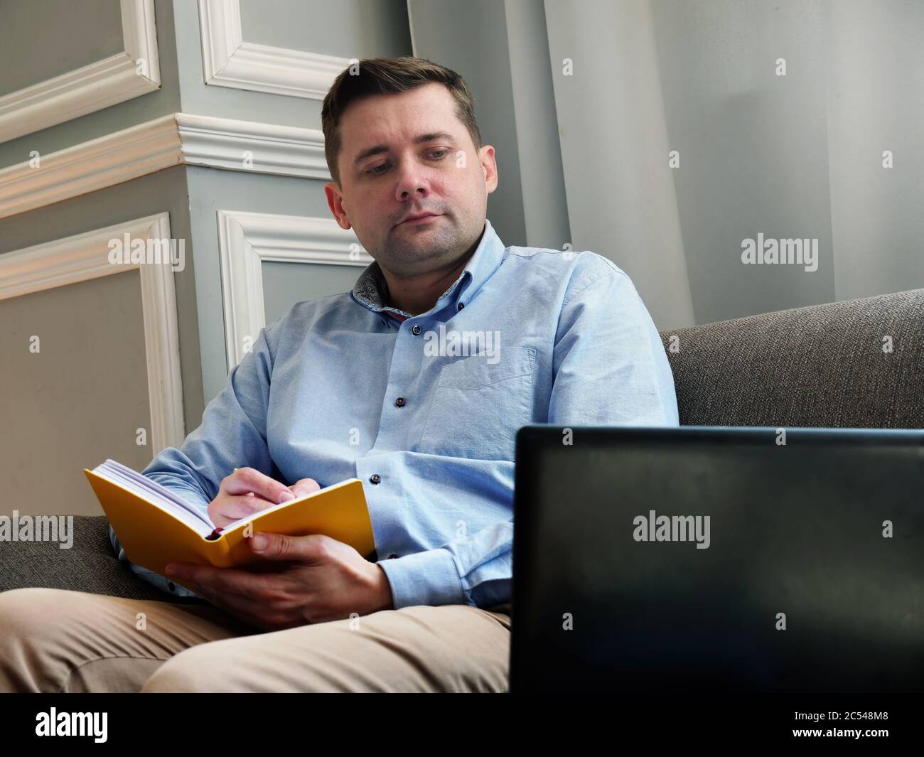 Work from home. A man checks the data and works while sitting on the couch. Stock Photo