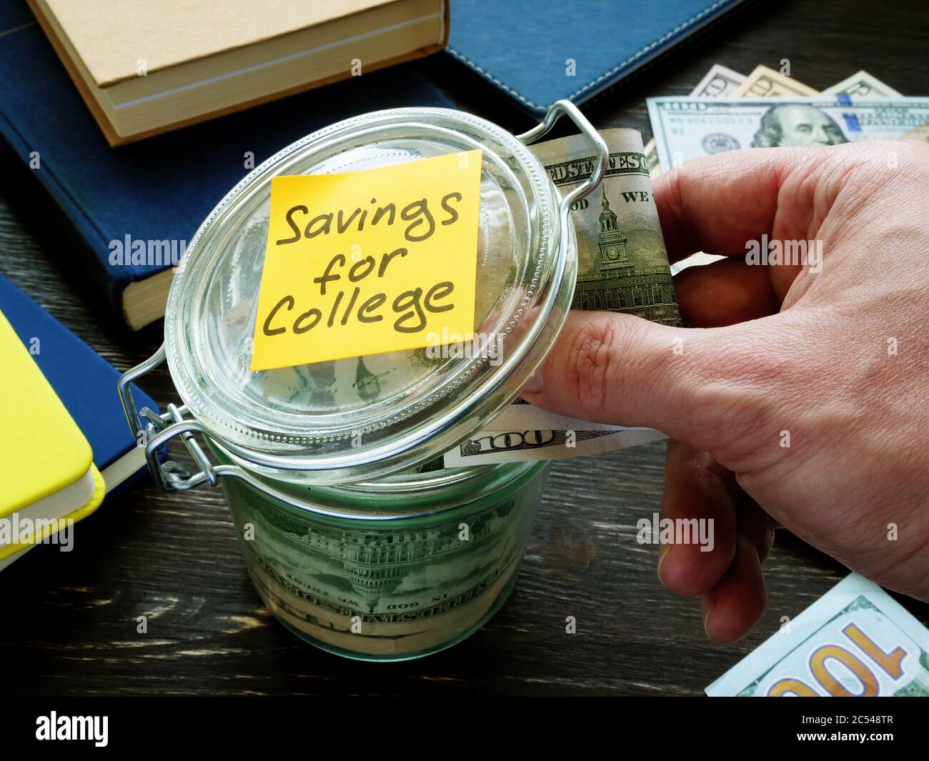 Savings for college. Hand puts money in a glass jar. Stock Photo