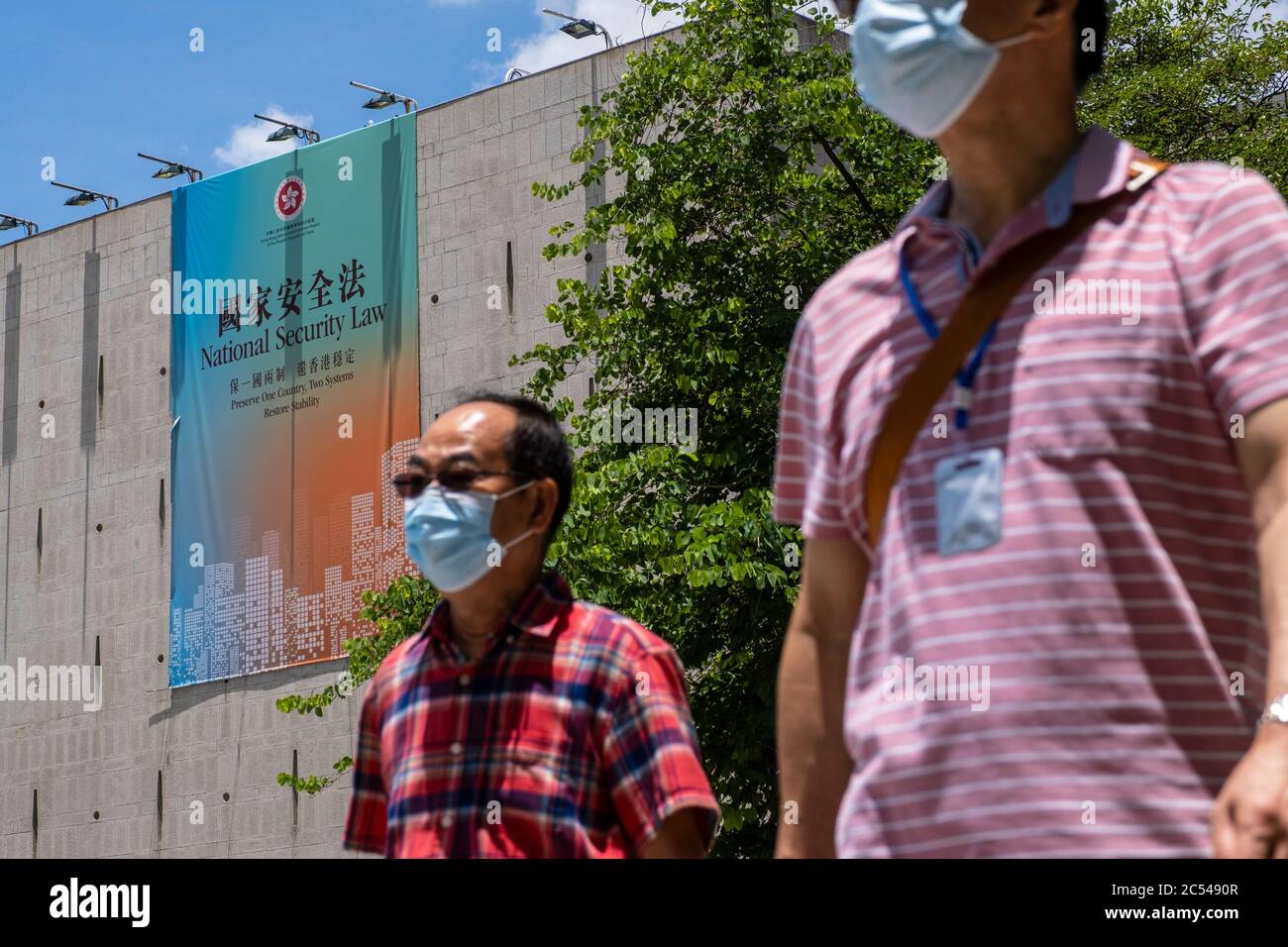 Pedestrians walk past a government sponsored advertisement promoting the new national security law in Hong Kong. Stock Photo