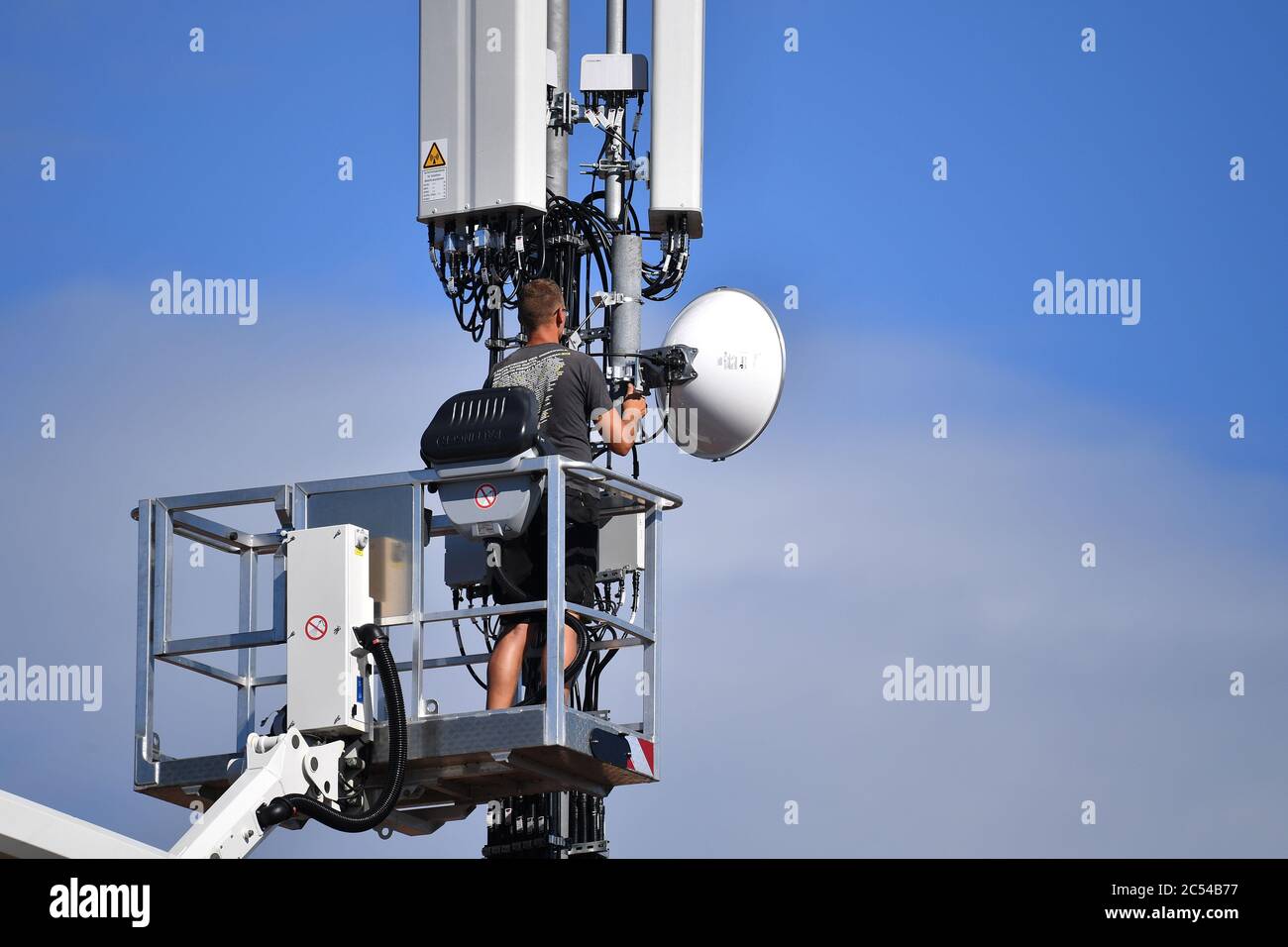 Hair, Deutschland. 30th June, 2020. Cell tower on a house roof. Worker  stands on a lifting