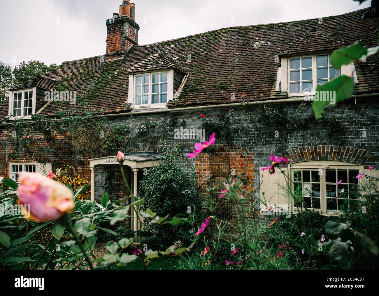 Charming medieval house with blooming pink roses in the village of Wickham, Hampshire, United Kingdom on a cloudy, moody day Stock Photo