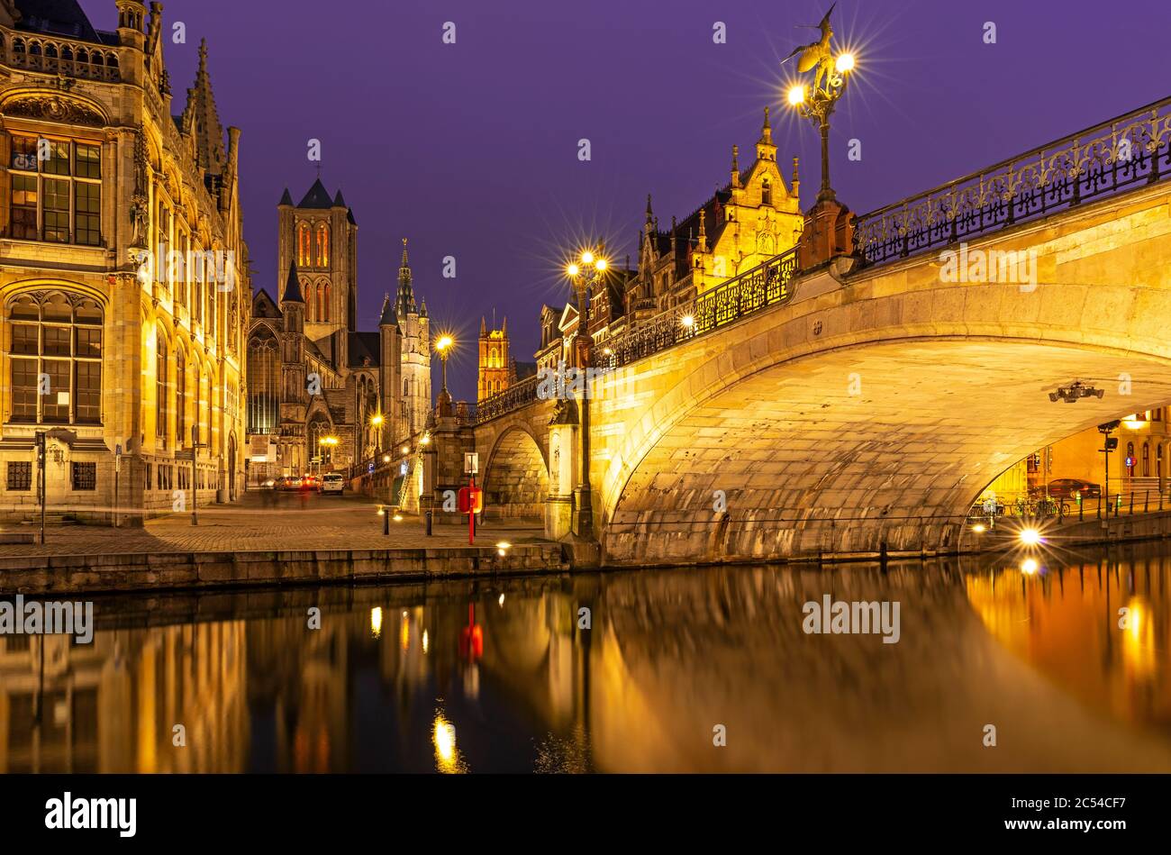The Saint Michael Bridge and the belfry tower of Gent (Ghent) with a reflection in the Leie river by the Graslei at night, East Flanders, Belgium. Stock Photo