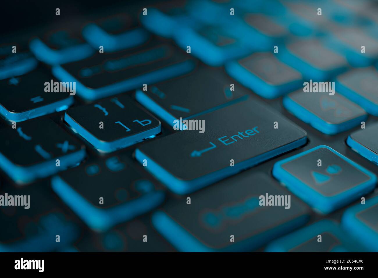 Blue backlit computer keyboard macro shot of enter key Stock Photo