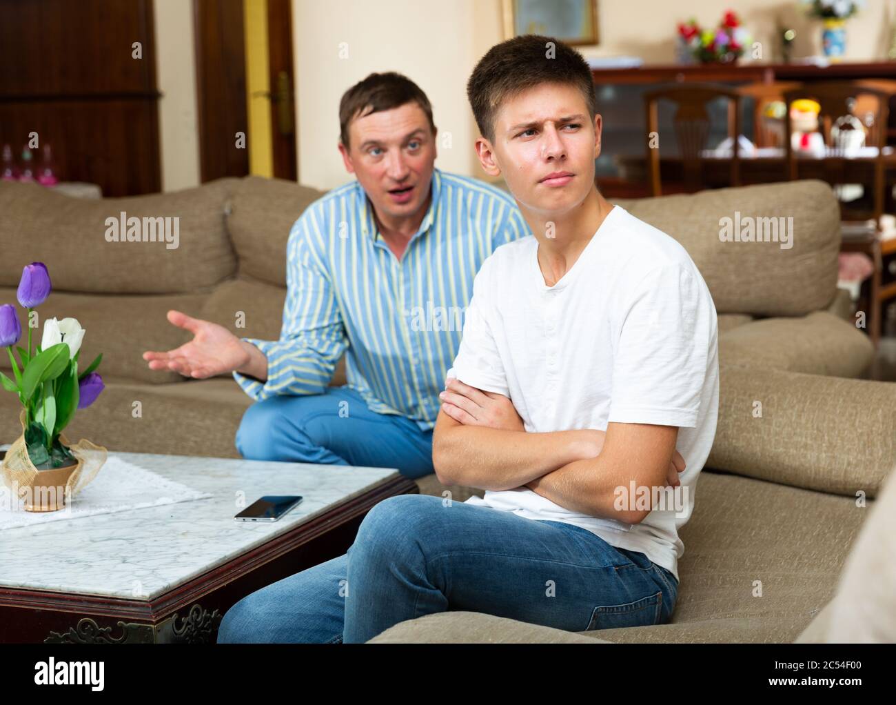 Angry adult man scolding his offended young son in living room Stock ...