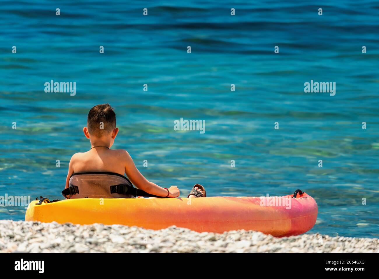Back view of happy teenage boy on a kayak at azure lagoon. Children in kayak at sea. Active vacation with young kid. Holiday activity with child Stock Photo