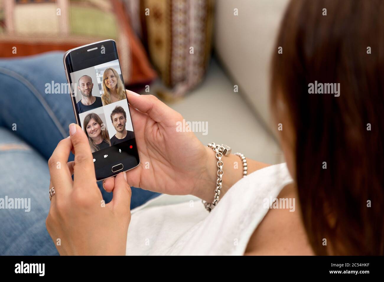 Video conference with a group of people. Young woman having a video chat with many people on her mobile phone. Stock Photo