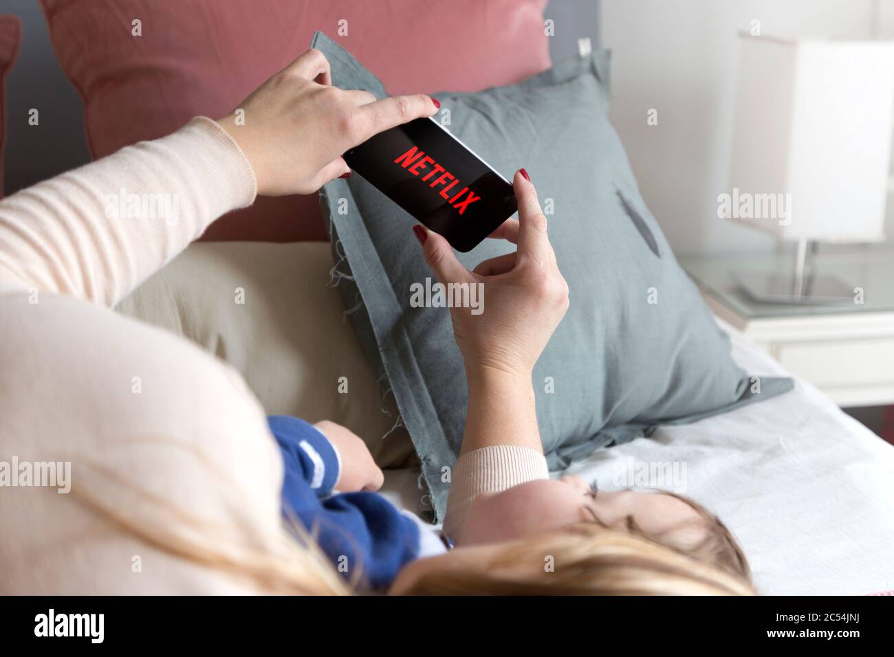 ROSARIO, SANTA FE, ARGENTINA - SEPTEMBER 2, 2019: Woman with her son watching a cell phone with netflix logo on screen. Stock Photo