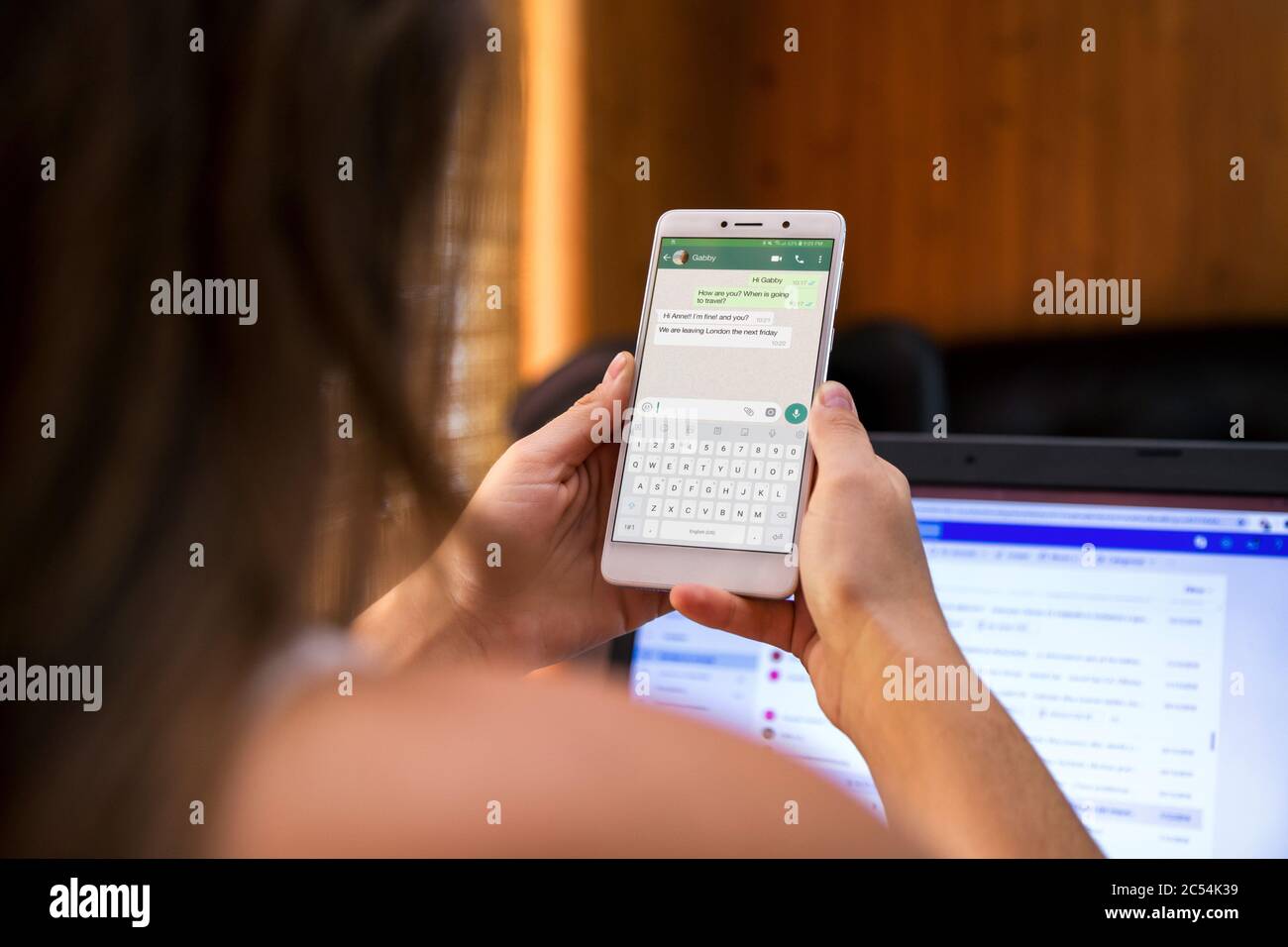 Girl chating through whatsapp. Shes with smartphone in her hands and a whats app conversation on screen. Stock Photo