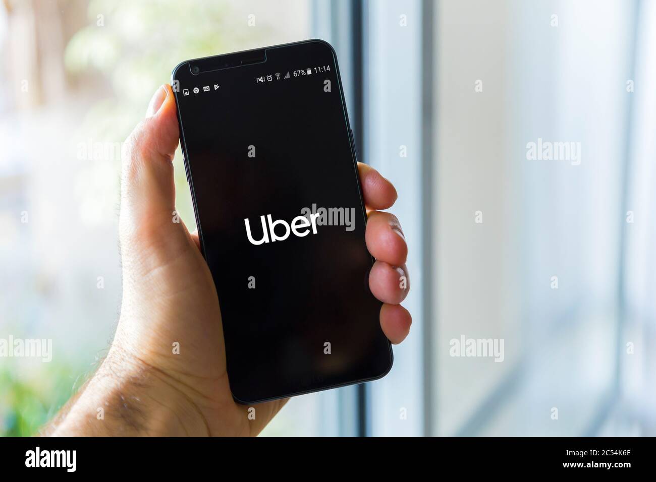 Phone showing Uber app on screen. Uber is smartphone app to rent taxi or car. International transportation network. Application. Stock Photo